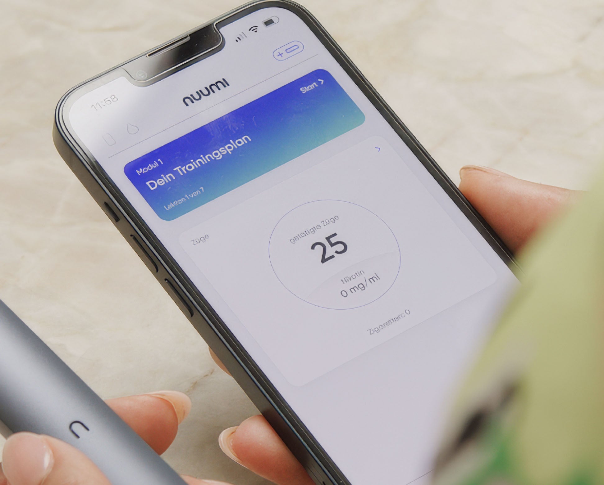 Ein Smartphone zeigt die nuumi-App mit einem Trainingsplan-Interface, das den Fortschritt mit 25 Zügen und 0 mg/ml Nikotinstärke anzeigt. Im Vordergrund ist ein grauer nuumi-Vaporizer in der Hand einer Person zu sehen